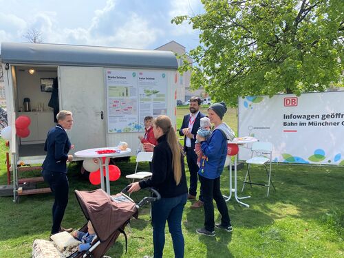 Mehrere Personen im Gespräch mit DB-Mitarbeitenden vor dem Infowagen